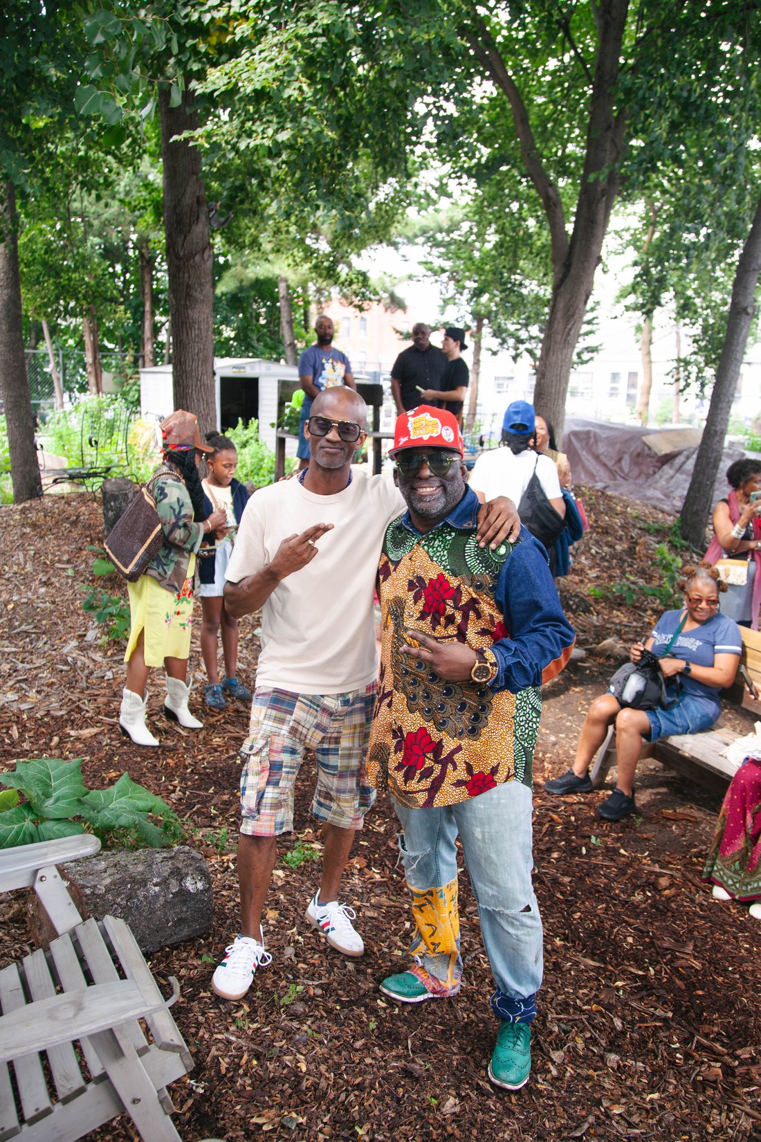Russell Frederick and Dahkil Hausif with their arms around each other in the Seeds of Somers Garden, surrounded by visitors.