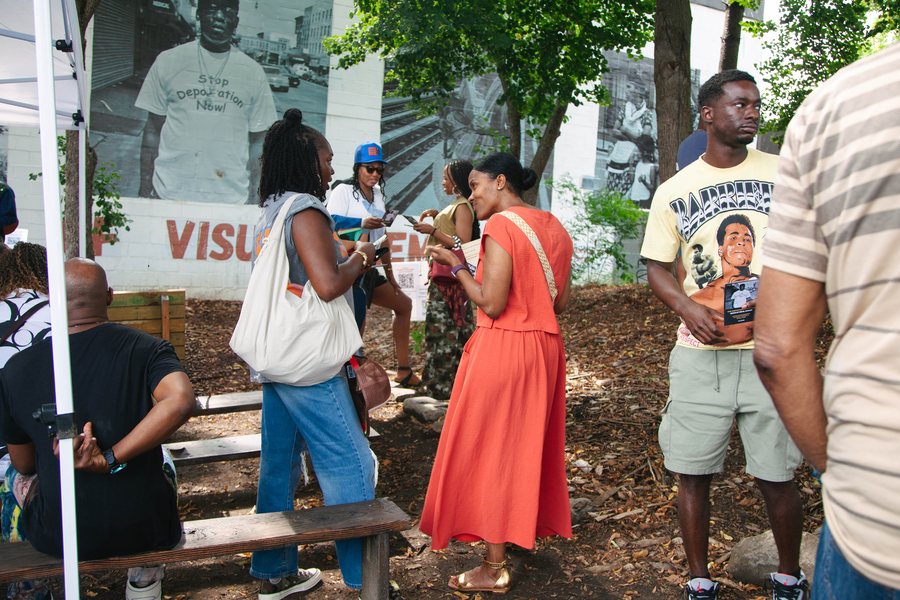 Visitors talking and reading cards at the garden, the mural behind them.